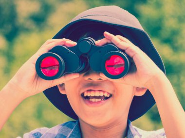Genç çocuk güneşli bir yaz gününde dürbünle mutluluktan bakıyor..