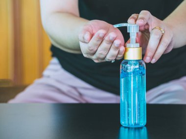 Asyalı kadın şişeden alkol jeli sürüyor ve temizlik için dezenfektan jeli yıkıyor, Covid-19 virüsünü korumak için bakteri ve virüs temizliyor. Pandemik koruma, hijyenik konsept