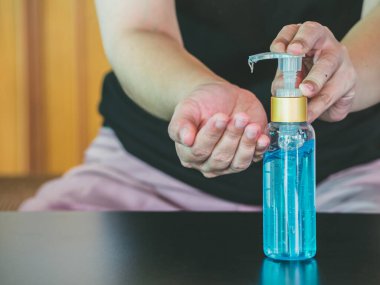 Asyalı kadın şişeden alkol jeli sürüyor ve temizlik için dezenfektan jeli yıkıyor, Covid-19 virüsünü korumak için bakteri ve virüs temizliyor. Pandemik koruma, hijyenik konsept