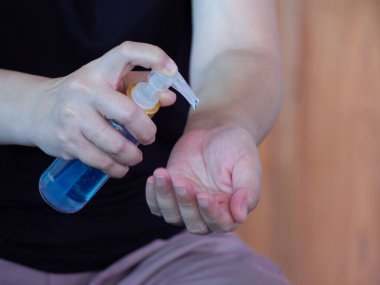 Asyalı kadın şişeden alkol jeli sürüyor ve temizlik için dezenfektan jeli yıkıyor, Covid-19 virüsünü korumak için bakteri ve virüs temizliyor. Pandemik koruma, hijyenik konsept