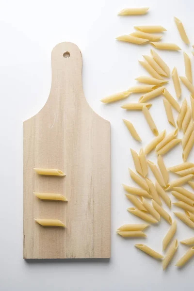 Pasta penne with cutting board — Stock Photo, Image