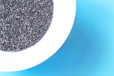 Mavi arka planda bir tabakta Chia tohumları. Düz yatıyordu