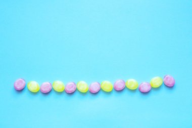 Mavi arka planda sıraya dizilmiş çok renkli şekerler. Kopyalama alanı olan. Düz yatıyordu