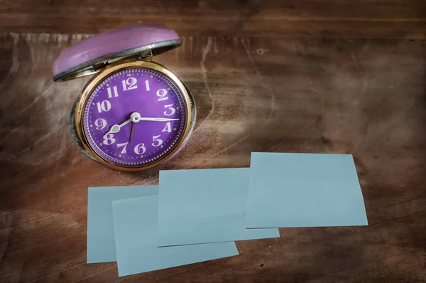 Relógio de alarme retrô e quatro notas pegajosas na mesa de madeira — Fotografia de Stock