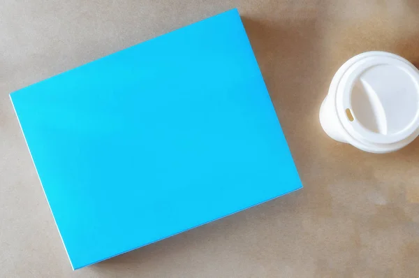 Libro bianco blu con tazza di caffè su sfondo marrone, spazio copia per l'idea di testo — Foto Stock