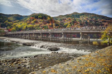 Kyoto, Japonya - 26 Kasım 2019: Arashiyama bölgesinde sonbahar mevsiminde akçaağaç dağı renkli Togetsu-kyo-Bridge manzarası