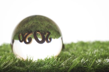 Wooden number 2020 reflection on glass crystal ball, unique happy new year concept and natural background idea