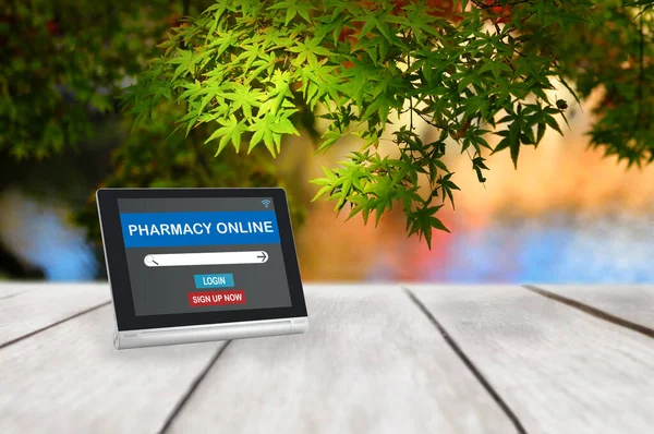Pharmacy online application with search bar on computer tablet on wooden plank and maple leaves tree background, healthcare everywhere concept and smart technology idea