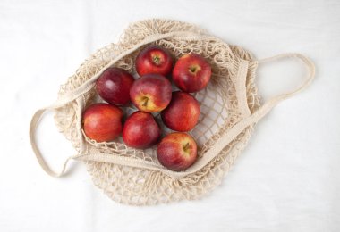 Beyaz arka planda elmalarla dolu bir alışveriş çantası. Yukarıdan manzara. Sıfır atık, plastiksiz konsept. Sağlıklı beslenme ve detoksifikasyon. Yaz meyveleri. Düz yatıyordu