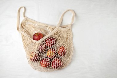 Beyaz arka planda elmalarla dolu bir alışveriş çantası. Yukarıdan manzara. Sıfır atık, plastiksiz konsept. Sağlıklı beslenme ve detoksifikasyon. Yaz meyveleri. Düz konum kopyalama alanı