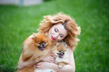  Güzel kızıl saçlı, zevkten gözleri kapalı bir kadın iki küçük köpeğe sarılıyor. Mutlu bir çocuk portresi Özgür bir kadın