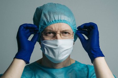 Coronavirus COVID-19 2019-NCoV tıbbi maskeli, bornozlu ve tıbbi şapkalı adam.