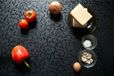 Siyah masa arkaplanlı pizza ürünleri peynir tereyağlı sosis mayalı domates biberi