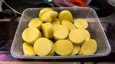 Mutfak lavabosunun yanındaki plastik bir kapta daire şeklinde kesilmiş çiğ tofunun yakın görüntüsü. Yumuşak tofu, ipek tofunun Çin usulü eşdeğeridir. Görüntü biraz bulanık.