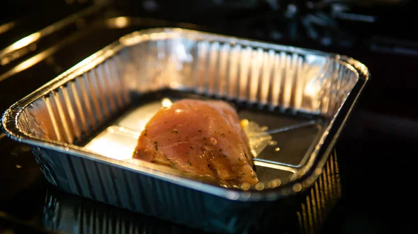 一块生鸡胸肉 里面是铝箔盒里的调味料 烤箱里可以烤 — 图库照片