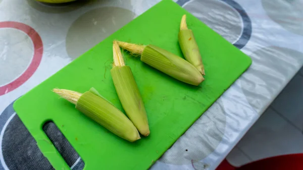 在厨房桌上的绿色切菜板上 可以看到生玉米的近景 作为配料添加到蔬菜汤中 — 图库照片