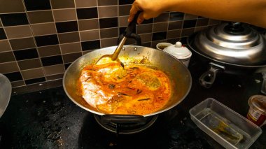 El, balığı daha lezzetli yapmak için spatula kullanarak balık kafasındaki körinin içine biraz hindistan cevizi sütü karıştırdı. Balık kafası körisi, Malezya mutfağında Hint ve Çin kökenli bir yemektir..