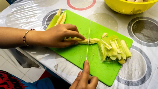 把婴儿的玉米切割成几片用来烹调配料做蔬菜汤 在绿色的刀片上切下婴儿玉米 — 图库照片