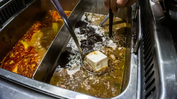 一个金属勺把冷豆腐浸入沸腾的汤中的近景 — 图库照片