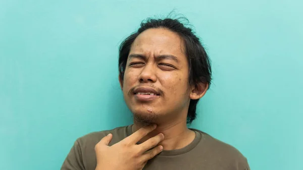 一个马来人牵着脖子的画像 喉咙酸痛 脸上有痛苦的反应 背景是孤立的蓝色 医学概念 有选择的重点 — 图库照片