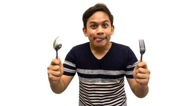年轻的亚裔马来人 身穿条纹T恤衫 拿着勺子和叉子准备吃东西 脸上的滑稽而饥饿的表情 舔嘴唇 想吃饭 节食和健康食品的概念 — 图库照片