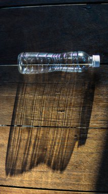 Dışarıdan gelen güneş ışınları ahşap zemindeki küçük plastik şişeye yansıyarak büyük bir şişe gölgesi oluşturdu. İlham verici ve gizli fırsatlar konsepti. Küçük dış benlik, büyük iç benlik..