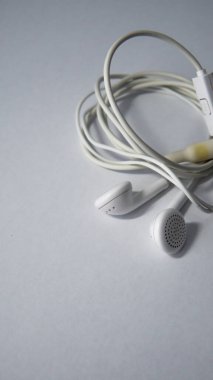 İzole edilmiş beyaz bir arkaplanda beyaz, birbirine dolanmış bir kulaklığın görüntüsünü kapat.