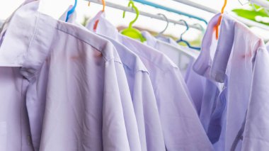 Dışarıdaki elbise askısında güneşin altında kuruyan öğrenciler için beyaz okul üniformasını yakından izleyin. Okula geri dön..