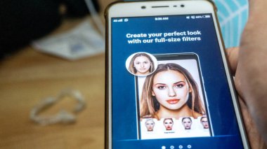 Sungai Buloh, Malaysia - July 20, 2019: An Android smartphone shows FaceApp application logo on the screen. Apps that edit highly realistic transformations of faces in photographs. clipart