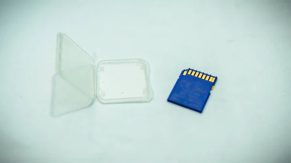 A blue SD Card and a transparent cover cases for protection on a white table.
