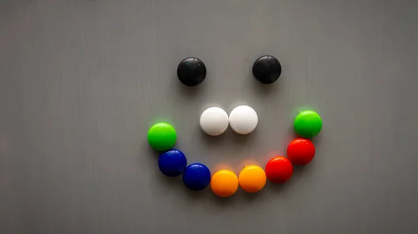 Smiley emoji using the colorful fridge magnet on the refrigerator. Art and creative concept. Kids toy. Selective angle and focus.