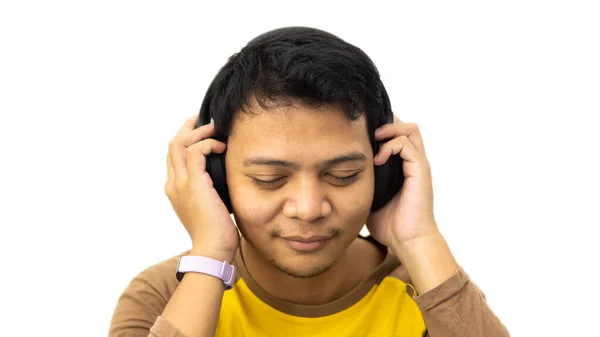 将耳机放在头上 两只手拿在白色孤立的背景上 将快乐的亚洲男人的近照挂在头上 一边微笑 一边深情聆听音乐 — 图库照片