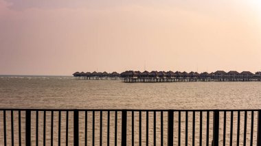 Gün batımında Bagan Lalang Sahili 'ndeki AVANI Sepang Goldcoast Oteli' nde özel balkonları olan deniz aşırı villaların manzarası..