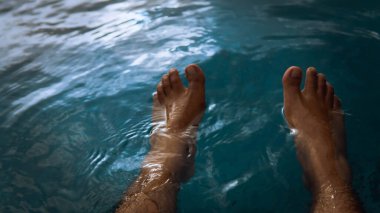 Oteldeki yüzme havuzundan su sıçratarak eğlenen bir adam yaz boyunca gün ışığıyla parlayan bir adam. Karanlık ve kasvetli bir konsept. Seçici görünüm.