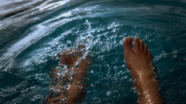 Oteldeki yüzme havuzundan su sıçratarak eğlenen bir adam yaz boyunca gün ışığıyla parlayan bir adam. Karanlık ve kasvetli bir konsept. Seçici görünüm.