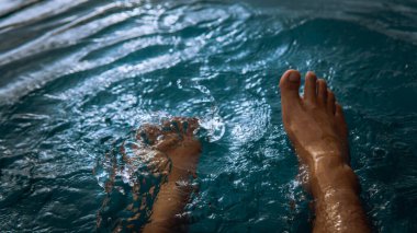 Oteldeki yüzme havuzundan su sıçratarak eğlenen bir adam yaz boyunca gün ışığıyla parlayan bir adam. Karanlık ve kasvetli bir konsept. Seçici görünüm.