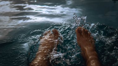 Oteldeki yüzme havuzundan su sıçratarak eğlenen bir adam yaz boyunca gün ışığıyla parlayan bir adam. Karanlık ve kasvetli bir konsept. Seçici görünüm.