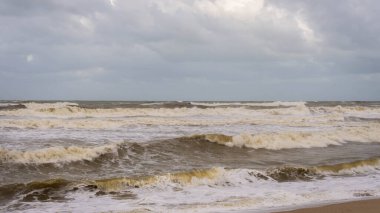 Muson mevsiminde Kuala Terengganu 'daki Batu Buruk Sahili' ni büyük dalgalar vurdu. Okyanustan esen güçlü rüzgar kıyı şeridini vurdu. Karanlık ve bulutlu bir arka plan. Denizle oynamak tehlikelidir. Fırtınalı deniz.