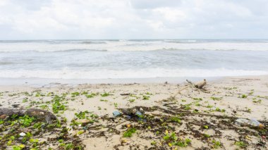 Kirli sahili olan güzel bir okyanus manzarası. Kuala Terengganu 'daki Batu Burok Sahili' nde plastik çöp ve tıbbi atık malzemeleriyle kumlu sahilde büyük bir mavi okyanus dalgası. Görüntü biraz bulanık.