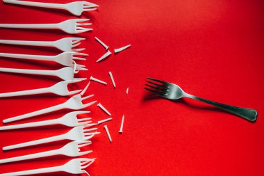Bir sürü plastik çatal ve kırmızı arka plan üzerinde bir metal.