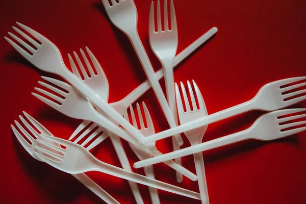 A lot of plastic forks on a red background. — Stock Photo, Image