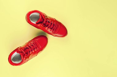 Pastel sarı arka planda kırmızı spor ayakkabılar. Spor anlayışı ve sağlıklı yaşam tarzı