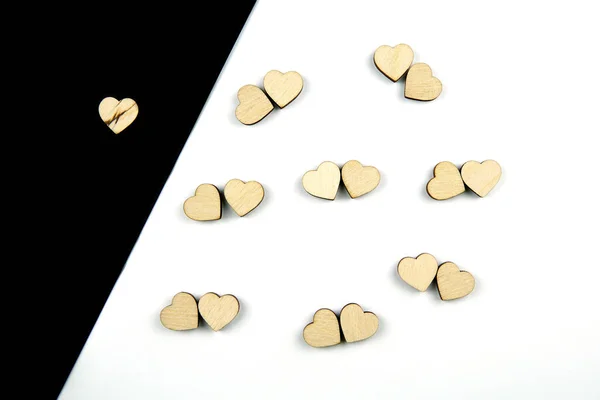 Muchos corazones de madera colocados por pares sobre fondo blanco y uno sobre fondo negro . — Foto de Stock