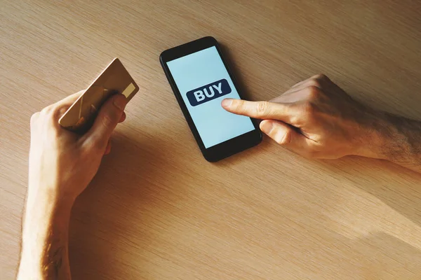 Hands, smartphone with a button to buy and bank card.