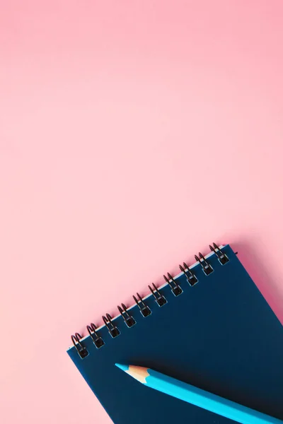 Um lápis e um caderno sobre um fundo rosa . Fotos De Bancos De Imagens