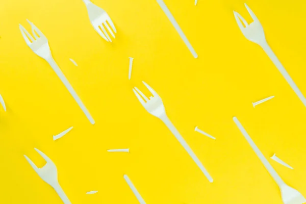 Pattern of broken plastic forks on a yellow background. — Stock Photo, Image