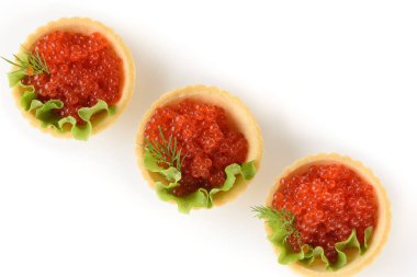 Beyaz arka planda yeşil salatalı hamur tartlarında kırmızı havyar.