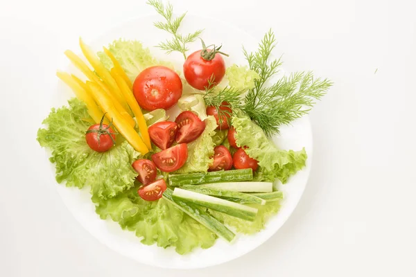 Свежие овощи лежат на зеленых листьях. Помидоры, огурцы, желтый перец, салат изолированы на белом фоне . — стоковое фото