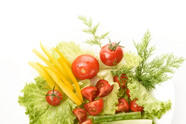 Свежие овощи лежат на зеленых листьях. Помидоры, огурцы, желтый перец, салат изолированы на белом фоне . — стоковое фото