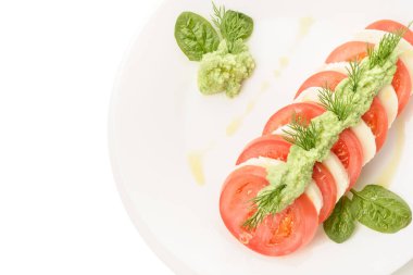 Domatesli Caprese salatası, mozzarella, ıspanak ve pesto.